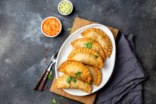 Latin American fried empanadas with tomato and avocado sauces. Top view.