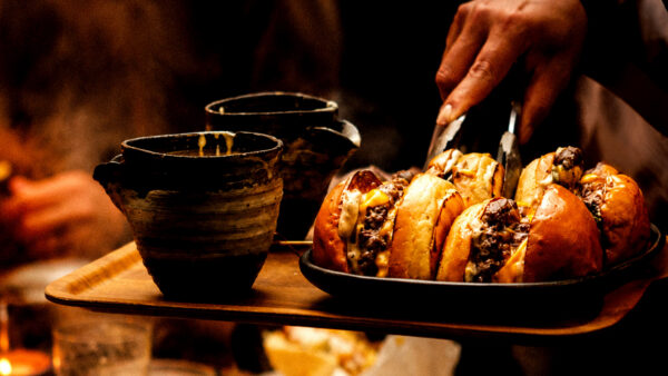 The Shoji Burger is made with American cheese, caramelized onions, pickled cucumbers and jalapenos, served on beef tallow brioche and in a a sizzling cheese fondue skillet ($28).
