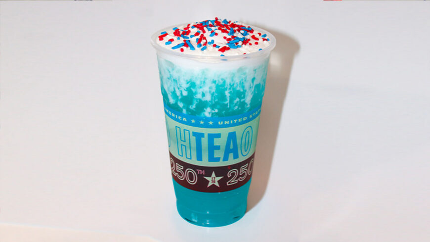 Blue frozen drink topped with whipped cream and red, white, and blue sprinkles in an HTeaO branded cup celebrating America's 250th anniversary.