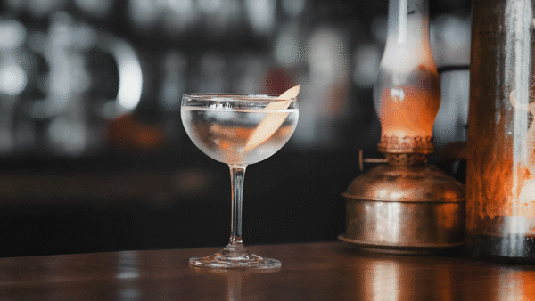 Martini sits on bar with blurred bottles behind it
