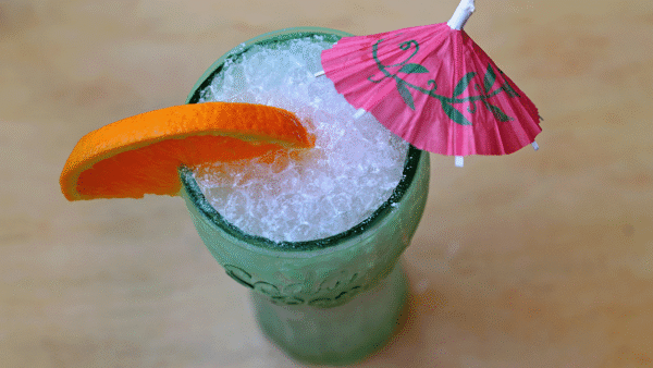 Dirty soda with crushed ice in a blue glass with an orange slice garnish