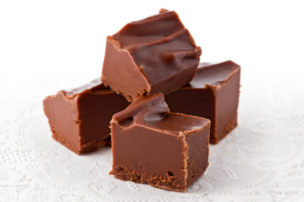 Four pieces of chocolate fudge on a white doily.