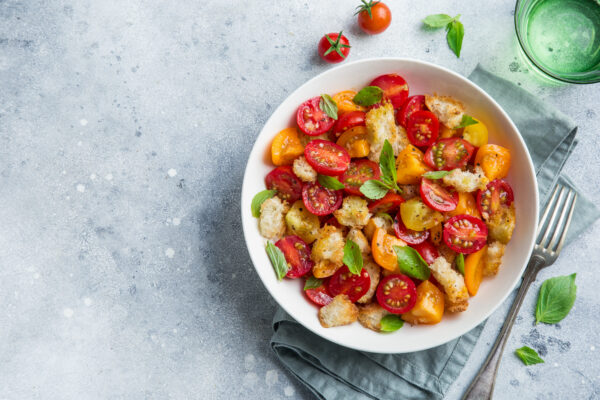 panzanella, traditional italian tomato and bread salad in white bowl, top view, copy space