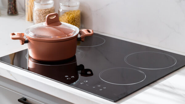 pink cooking pot on top of a black glass cooktop