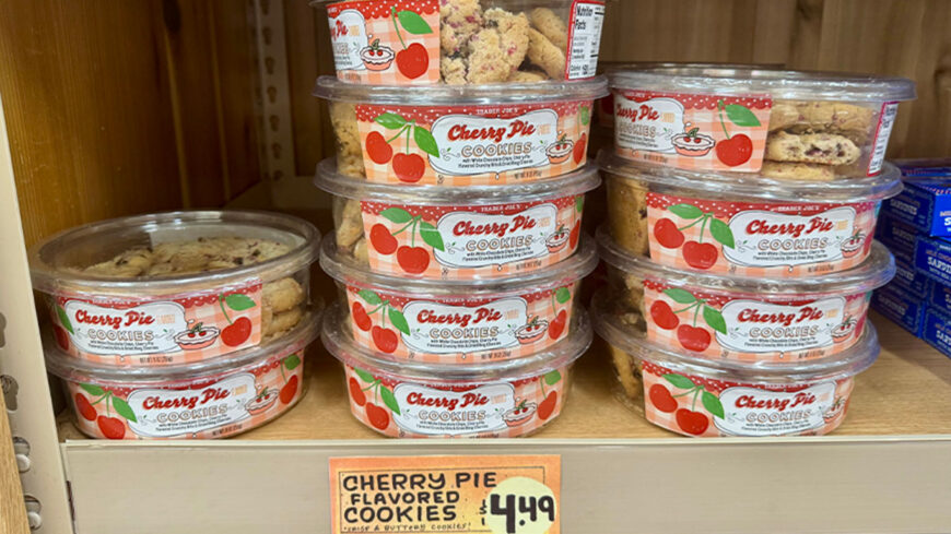 Trader Joe’s Cherry Pie Cookies in clear plastic containers, stacked on a store shelf, with cherry-themed packaging and a $4.49 price sign.