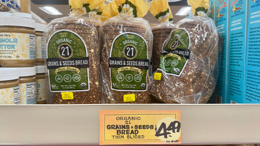 Trader Joe’s Organic 21 Grains & Seeds Bread in thin-sliced packaging, displayed on a grocery store shelf with a $4.49 price sign.