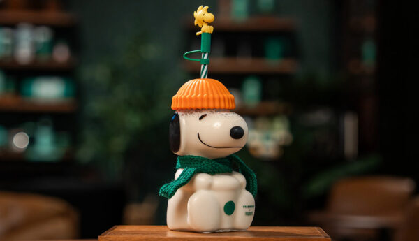 Snoopy-shaped glass cup with orange hat and Woodstock straw topper