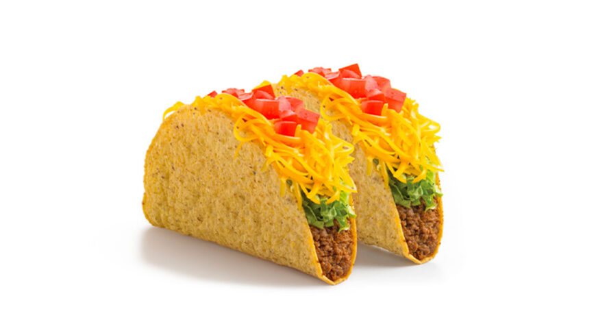 Two crunchy tacos filled with seasoned ground beef, shredded lettuce, cheddar cheese, and diced tomatoes on a white background.