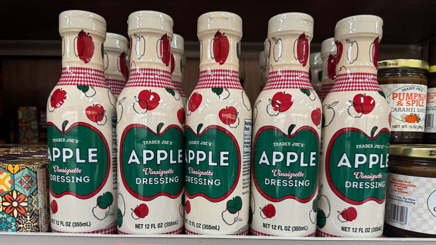 Several bottles of Trader Joe’s Apple Vinaigrette Dressing with cream-colored labels decorated with red and green apples.