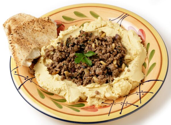A plate of hummus chickpea dip filled with fried lamb mince, onion, pine nuts and parsley, known as hummus bil lahme.