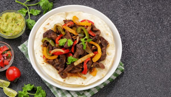 Beef fajitas made with tender strips of seasoned beef, colorful bell peppers, and onions, served hot with soft flour tortillas. Tex-Mex food
