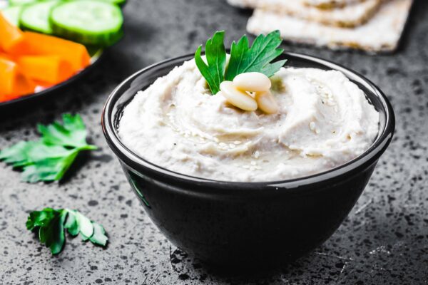 white bean dip on dark concrete background. Selective focus, space for text.