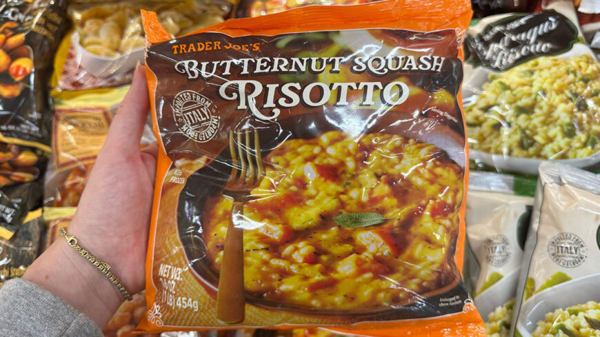 A package of Trader Joe’s Butternut Squash Risotto held in a hand, showing creamy risotto with pieces of squash.