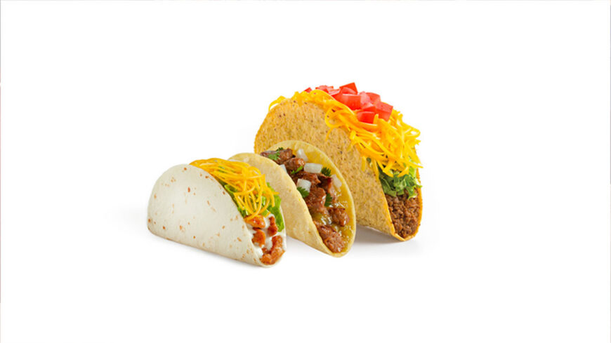 Three tacos featuring soft and crunchy shells, filled with seasoned meat, shredded cheese, lettuce, tomatoes, and other toppings, displayed against a white background.