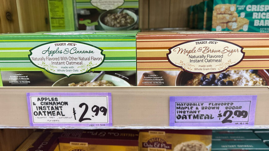 Trader Joe’s Apples & Cinnamon and Maple & Brown Sugar instant oatmeal boxes displayed on a store shelf, with price signs showing $2.99 each.