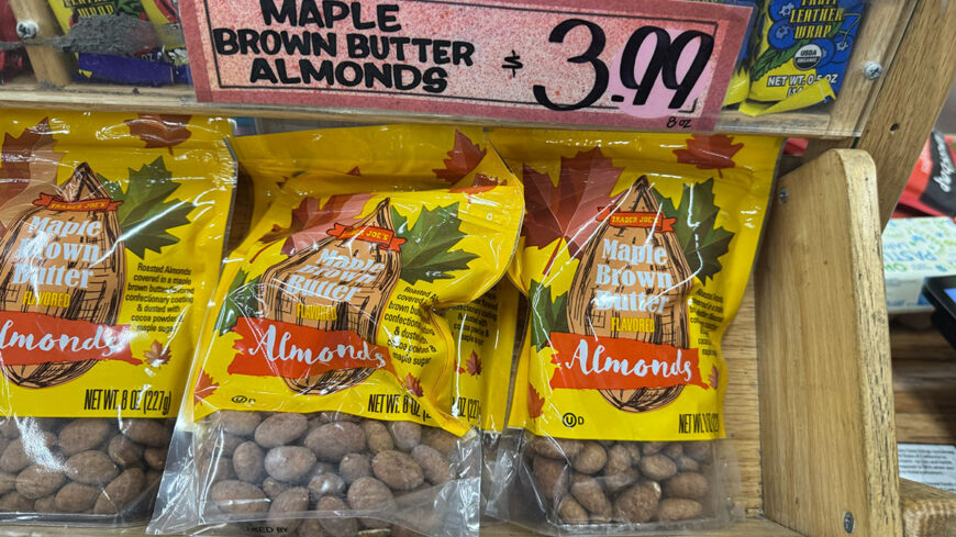 Bags of Trader Joe’s Maple Brown Butter flavored almonds in yellow packaging, displayed beneath a $3.99 price sign.