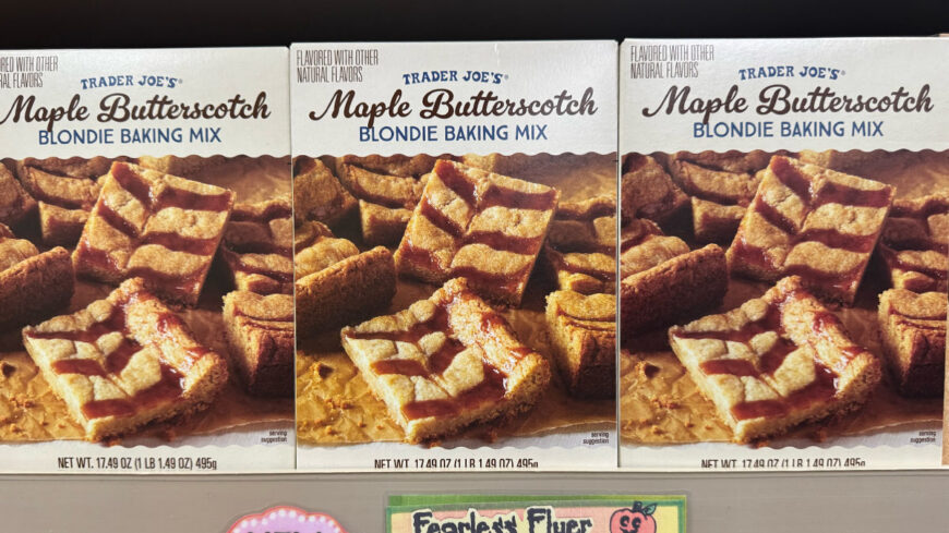Three boxes of Trader Joe’s Maple Butterscotch Blondie Baking Mix displayed on a store shelf, with photos of golden blondies on the packaging.