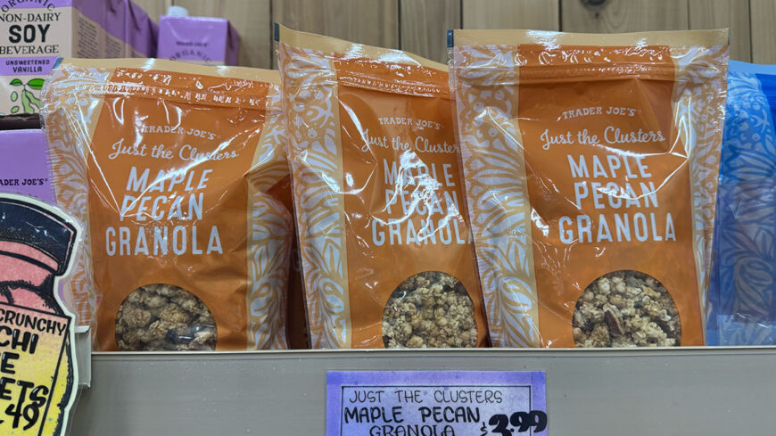 Three bags of Trader Joe’s Just the Clusters Maple Pecan Granola displayed on a store shelf, with a shelf price sign below.