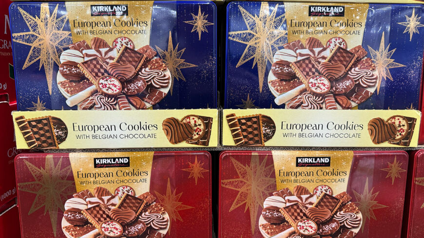 Costco display of Kirkland Signature European cookies with Belgian chocolate in decorative blue and red tins, featuring assorted chocolate-covered cookies.