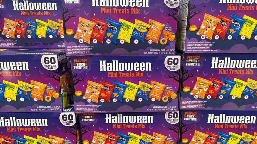 Stacked boxes of Halloween Mini Treats Mix featuring assorted mini Cheetos, Doritos, Funyuns, Rold Gold pretzels, and SunChips bags.