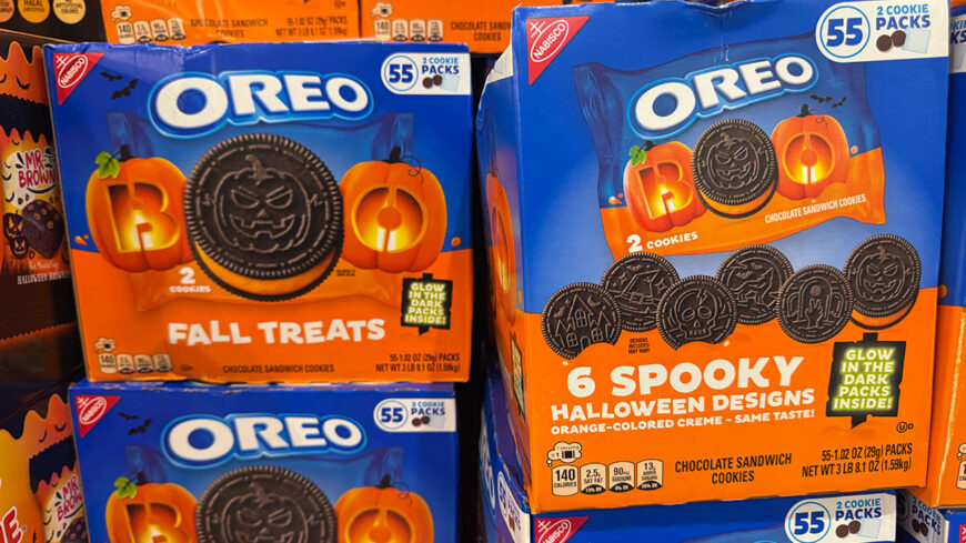 Display of Oreo Halloween chocolate sandwich cookies in blue and orange packages, featuring pumpkin-themed designs and six spooky cookie designs.