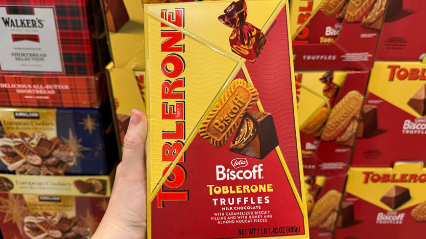A hand holds a box of Lotus Biscoff Toblerone truffles, milk chocolate with caramelized biscuit filling, displayed among other chocolate gift boxes.