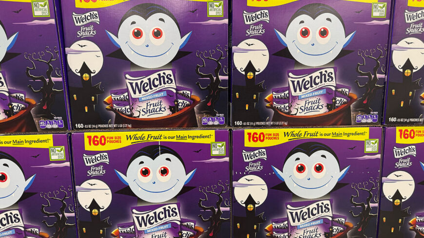 Stacked boxes of Welch’s Fruit Snacks in a purple Halloween-themed package featuring a cartoon vampire, bats, a haunted house, and the text “160 fun size pouches.”